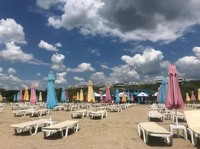 a group of chairs and umbrellas on a beach at Sea Sunrise Apartment in Burgas City