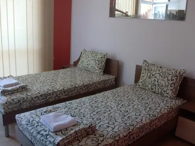 a room with two beds and a chair at Guest House Nedelchevi in Primorsko