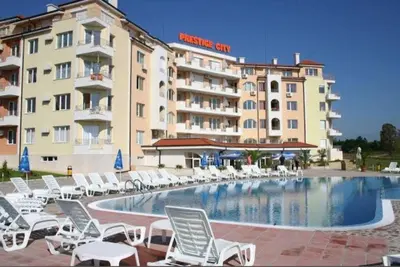 a hotel with chairs and a swimming pool and a building at Apartament Prestig Sity in Sunny Beach