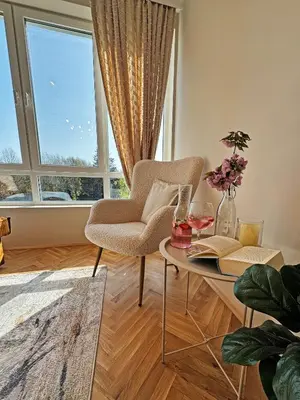 a living room with a chair and a table and a window at AURA BEACH apartment in Burgas City