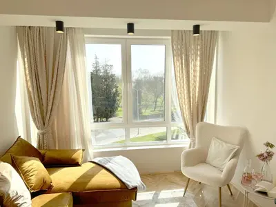 a bedroom with a bed and a chair and a window at AURA BEACH apartment in Burgas City
