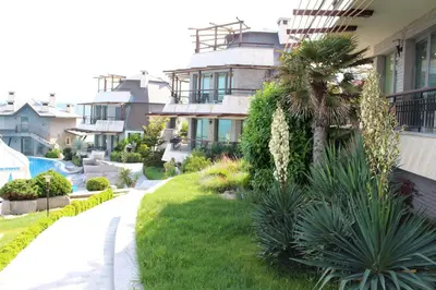 a house with a green yard next to a building at Art Complex Anel in Sozopol