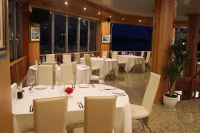a restaurant with white tables and chairs and a large screen at Art Complex Anel in Sozopol