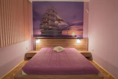 a bedroom with a bed with a painting of a ship at Sea Garden Plaza Apartment - Free Parking in Burgas City