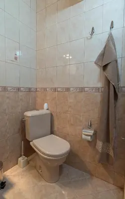a bathroom with a toilet and a tiled wall at Sea Garden Plaza Apartment - Free Parking in Burgas City