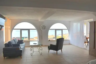 a living room with two arched windows and a couch and chairs at Вlue horizon in Sveti Vlas