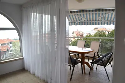 a room with a table and chairs and a balcony at Вlue horizon in Sveti Vlas