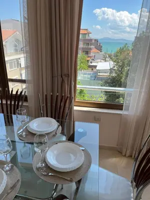 a glass table with chairs and a window with a view at Сарафово холидейс in Burgas City