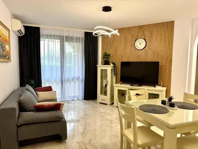 a living room with a couch a table and a tv at Przytulny apartament w Sweti Vlas 350m od morza in Burgas City