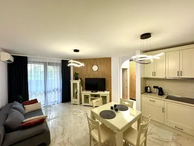 a kitchen and living room with a table and a couch at Przytulny apartament w Sweti Vlas 350m od morza in Burgas City