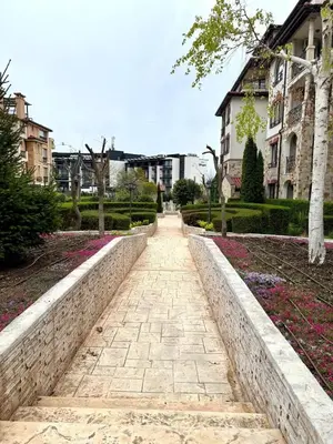a walkway in a park with flowers and buildings at Przytulny apartament w Sweti Vlas 350m od morza in Burgas City