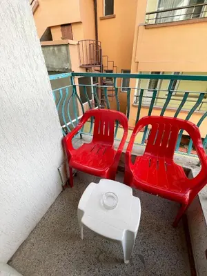 two red chairs and a table on a balcony at Bonne Chance Apartment Sozopol in Sozopol