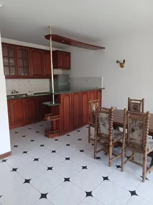 a kitchen with wooden cabinets and a table and chairs at Lazur Family Apartment Pomorie in Pomorie