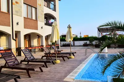 a hotel with a pool and chairs and umbrellas at Sea Club Sarafovo Apartments in Burgas City