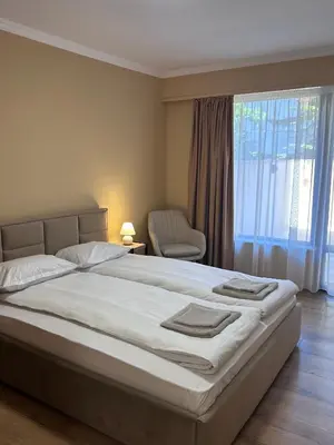 a bedroom with a large bed and a chair at Апартаменти Bella Deluxe in Ravda