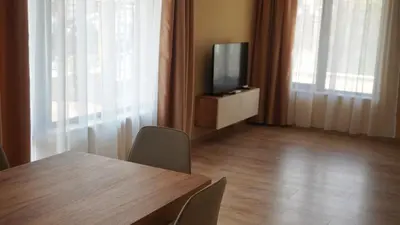a dining room with a table and a tv and curtains at Апартаменти Bella Deluxe in Ravda