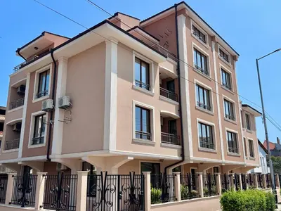 a large building with a fence in front of it at Апартаменти Bella Deluxe in Ravda