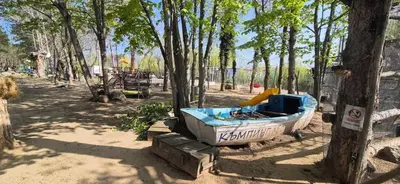 a boat sitting next to a tree in a park at Бунгало Шангри Ла - 2, плаж Градина in Sozopol