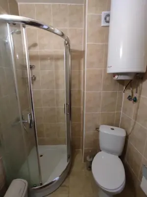 a bathroom with a shower and a white toilet at Double Cream Apartment in Tŭnkovo