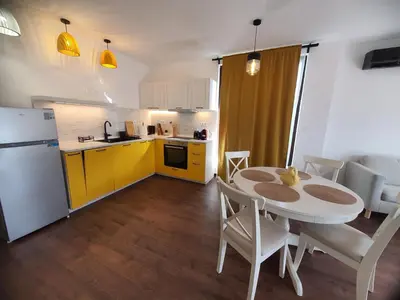a kitchen and dining room with a table and yellow cabinets at Вила Винсент - Villa Vincent in Lozenets