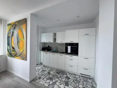 a kitchen with white cabinets and a painting on the wall at Luxus Art Apartament Burgas in Burgas City