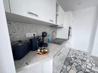 a kitchen with white cabinets and a counter top at Luxus Art Apartament Burgas in Burgas City