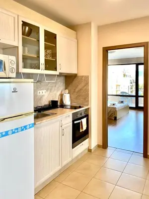 a kitchen with white cabinets and a white refrigerator at Premier Fort Beach Sveti Vlas in Sveti Vlas