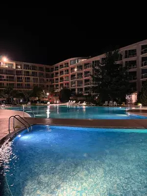 a large swimming pool in front of a building at night at Apartament Primavera Atlantis SPA in Burgas City