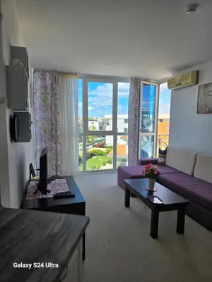 a living room with a purple couch and a large window at Apartament Primavera Atlantis SPA in Burgas City