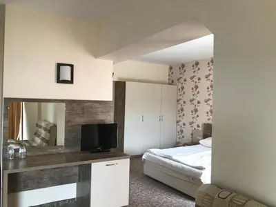 a bedroom with a bed and a desk with a television at Hotel Lira in Sunny Beach