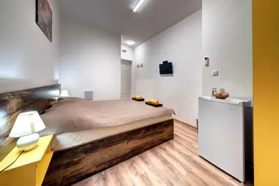 a bedroom with a large bed and a desk and a refrigerator at Neptun-Yellow in Primorsko