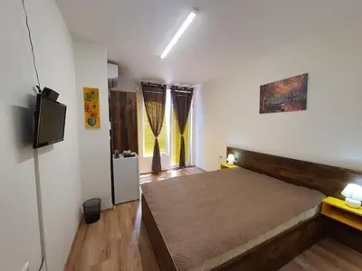 a bedroom with a large bed and a flat screen tv at Neptun-Yellow in Primorsko