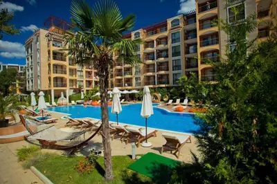 a hotel swimming pool with a palm tree and chairs and umbrellas at Nice 2 Room Apartment Harmony Suites 3 Sunnybeach in Sunny Beach