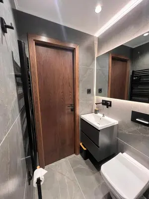 a bathroom with a toilet and a sink and a wooden door at Maxim Apartment with Free Parking in Varna City