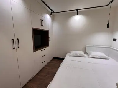 two beds in a room with white cabinets and a tv at Maxim Apartment with Free Parking in Varna City