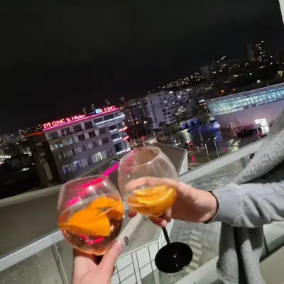 a person holding two glasses of wine on a balcony at Central park apartment Сентрал парк апартамент Бургас in Burgas City