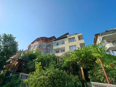 a tall building with trees in front of it at Rita's - family apartment by the sea in Primorsko