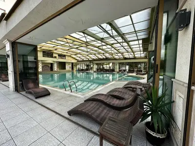 a swimming pool in a building with chairs and a building at Perfect Sea and Pool View Long Beach Apartment in Shkorpilovtsi