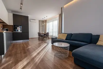 a living room with a blue couch and a table at Spacious, free parking, 3min beach, Flora Panorama in Burgas City