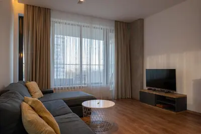 a living room with a couch and a flat screen tv at Spacious, free parking, 3min beach, Flora Panorama in Burgas City