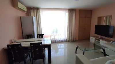 a living room with a table and chairs and a television at Double Peach Apartment in Sveti Vlas