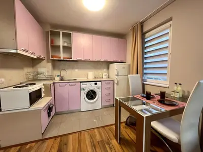 a kitchen with pink cabinets and a table in it at Cozy One-Bedroom Apartment near Burgas Sea Garden in Burgas City