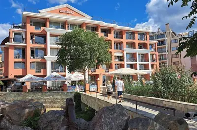 two people walking on a bridge in front of a building at Carina Beach - Private apartment - BSR - 1 in Sunny Beach