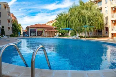 a large blue swimming pool with two buildings at Double Cherry Apartment in Sunny Beach