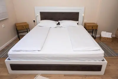 a large white bed in a room with two tables at Apartment Maria in Burgas City