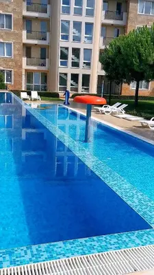 a large blue swimming pool in front of a building at Студио Черноморски залив Атия Резорт in Chernomorets