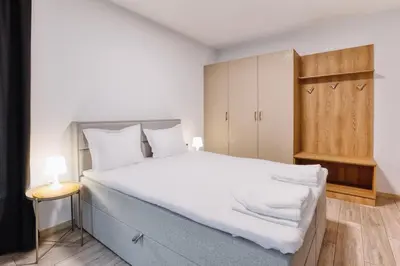 a bedroom with a large white bed and a wooden cabinet at Marina Bay Apartments Kraymorie in Burgas City