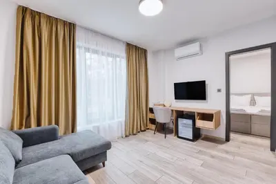 a living room with a couch and a desk with a television at Marina Bay Apartments Kraymorie in Burgas City