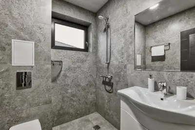 a bathroom with a sink and a toilet and a window at Marina Bay Apartments Kraymorie in Burgas City