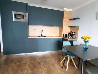 a kitchen with blue cabinets and a table at Panorama Sea View in Sveti Vlas